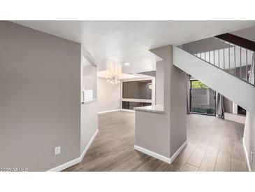 Bright, open-concept living room with wood floors and a modern lighting fixture at 3030 N Hayden Rd # 16, Scottsdale, AZ 85251