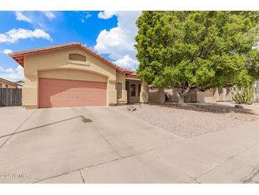Charming single-story home boasts a low-maintenance gravel front yard and a two-car garage with a pink door at 3668 E Cody Ave, Gilbert, AZ 85234