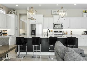 Open-concept kitchen with stainless steel appliances, granite island with chairs and modern pendant lighting at 1816 N Bernard Cir, Mesa, AZ 85207