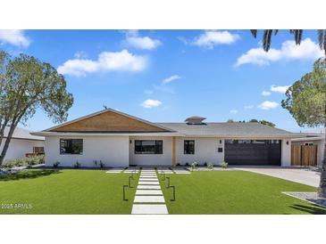 Inviting single-story home with manicured lawn, modern walkway, and neutral paint scheme under a partly cloudy blue sky at 8215 E Virginia Ave, Scottsdale, AZ 85257