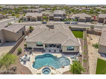 Aerial view of a backyard with a freeform pool, spa, patio, and lounge area, surrounded by desert landscaping and mountain views at 18120 W Cassia Way, Goodyear, AZ 85338