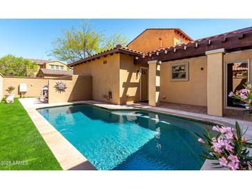 Refreshing backyard pool with cool turquoise water, surrounded by a stone patio and green artificial turf at 21152 W Sunrise Ln, Buckeye, AZ 85396