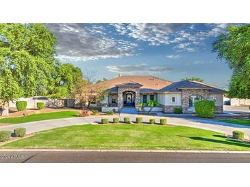 Beautiful single-story home with manicured lawn, circular driveway, and stone accents at 21470 E Orchard Ln, Queen Creek, AZ 85142