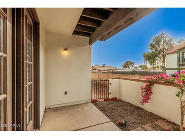 Enclosed patio featuring access door and an outdoor space with accent wall and beautiful flowering shrub at 2201 W Union Hills Dr # 119, Phoenix, AZ 85027