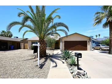 Charming single-story home featuring a well-maintained yard, desert landscaping, and a two-car garage at 2424 E Aster Dr, Phoenix, AZ 85032