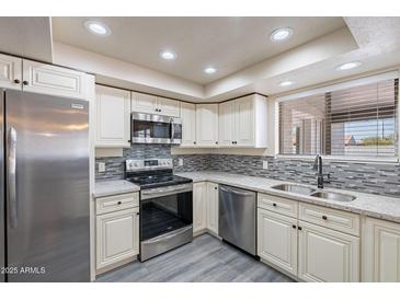 Modern kitchen featuring stainless steel appliances, light cabinets, and stone countertops at 2502 E Malibu Dr, Tempe, AZ 85282