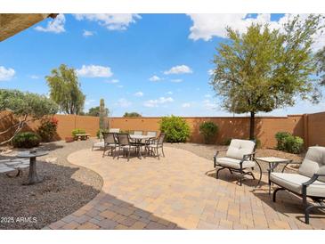 Beautiful backyard patio area with brick pavers, dining table and chairs, and comfortable outdoor seating at 27030 W Escuda Dr, Buckeye, AZ 85396