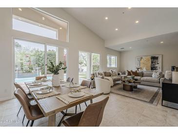 Open-concept living and dining area with view of the pool through large glass doors and lots of natural light at 9442 N 118Th St, Scottsdale, AZ 85259
