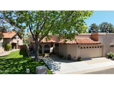 Charming home featuring a red tile roof, arched windows, and a well-manicured lawn, nestled under a mature shade tree at 11837 N 40Th Pl, Phoenix, AZ 85028