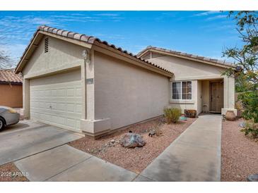 Inviting beige home featuring desert landscaping, a two-car garage, and a tile roof under a bright blue sky at 12048 W Dahlia Dr, El Mirage, AZ 85335