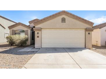 Beige one story home featuring a two car garage and low maintenance desert landscaping at 3323 W Fraktur Rd, Phoenix, AZ 85041