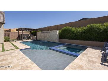 Inviting pool and spa area with a waterfall feature, surrounded by lush landscaping at 3429 E Constance Way, Phoenix, AZ 85042