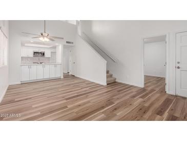 Bright living room featuring wood floors, stairs to second floor and open kitchen with white cabinets at 520 N Stapley Dr # 123, Mesa, AZ 85203