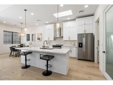 Stylish kitchen with white cabinetry, stainless steel appliances, a center island, and modern pendant lighting at 7955 E Chaparral Rd # 116, Scottsdale, AZ 85250