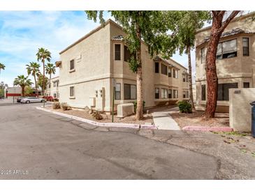 A three-story beige apartment building with desert landscaping under a clear sky at 925 S Longmore -- # 210, Mesa, AZ 85202