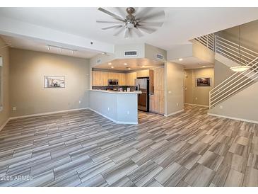 Open-concept living room with wood-style floors, modern lighting, and adjacent kitchen at 16 W Encanto Blvd # 2, Phoenix, AZ 85003