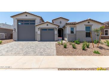Charming, light-colored single-Gathering home featuring a large garage, front yard landscaping, and a paver driveway at 23724 N 165Th Dr, Surprise, AZ 85387