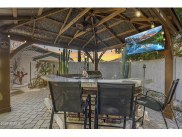 Outdoor kitchen and bar area featuring a grill, lighting, a fan, and a TV at 8246 W Melinda Ln, Peoria, AZ 85382