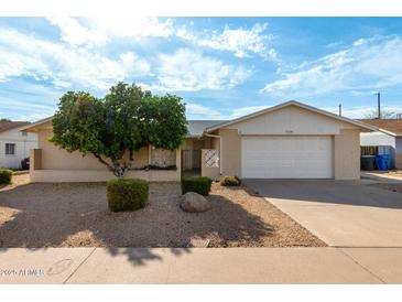 Charming single-level home with a two-car garage, desert landscaping, and a mature tree at 13148 N 21St Ave, Phoenix, AZ 85029