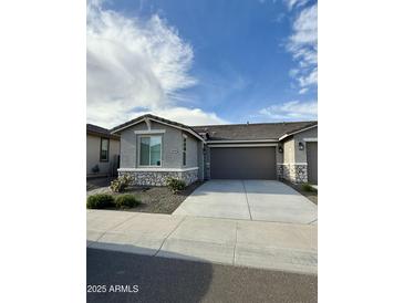 Charming single-story home with a stone facade, well-manicured landscaping, and a spacious two-car garage at 20610 W Vermont Ave, Buckeye, AZ 85396