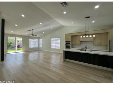 Open-concept living room with a modern kitchen, expansive windows, and stylish laminate flooring throughout at 20822 N 42Nd. Ave, Glendale, AZ 85308