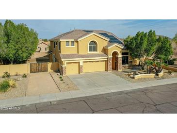 Two-story home featuring a three-car garage, desert landscaping, and solar panels on the roof at 25453 N 68Th Ln, Peoria, AZ 85383