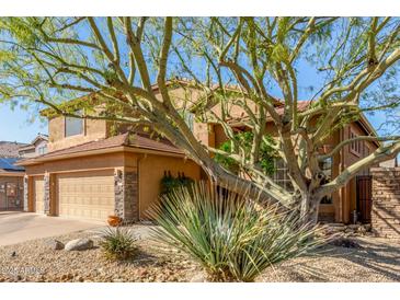 Inviting two-story home featuring a desert landscape and a three-car garage with stone accents at 3206 W Sentinel Rock Rd, Phoenix, AZ 85086