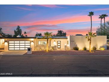 Contemporary home featuring a multi-car garage and stucco exterior complemented by desert landscaping at sunset at 9052 N 29Th St, Phoenix, AZ 85028
