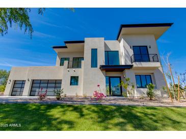 Modern two-story home featuring a stucco facade, black trim, a glass garage door, and landscaped yard at 100 W Northern Ave # 15, Phoenix, AZ 85021