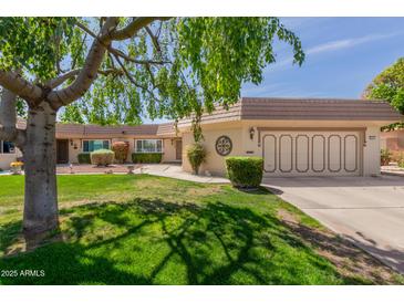 Charming single story home with a well-manicured lawn, mature landscaping, and a two car garage at 10461 W Hutton Dr, Sun City, AZ 85351