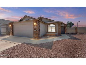 Charming single story home featuring brick accents, a two-car garage and desert landscaping at 1057 W Mesquite Ave, Apache Junction, AZ 85120