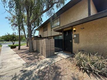Inviting exterior featuring stucco and a well-maintained front yard with mature trees and secure gated entry at 1706 W Village Way, Tempe, AZ 85282