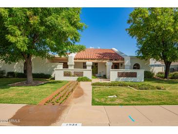 Charming single-story home featuring a red tile roof, lush landscaping, and mature shade trees in a well-maintained front yard at 1934 E Hale St, Mesa, AZ 85203