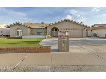Charming beige home with green turf lawn, arched windows, mailbox, and two car garage at 3907 W Sharon Ave, Phoenix, AZ 85029