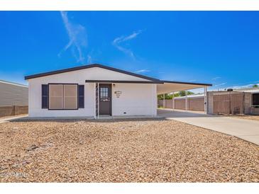 Charming single-story home featuring a gravel front yard, carport, and black and white trim at 7707 E Garnet Ave, Mesa, AZ 85209