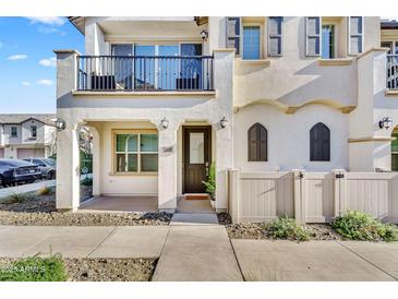 Charming two-story home featuring a balcony, arched windows, and a well-maintained front yard with a white picket fence at 9906 E Wavelength Ave, Mesa, AZ 85212
