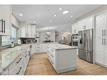 Open concept kitchen with white cabinets, granite countertops, and stainless steel appliances at 12411 N 57Th St, Scottsdale, AZ 85254