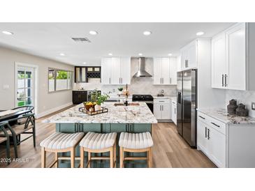 Bright kitchen boasts a large island with seating, stainless steel appliances, and white cabinets at 1012 E Magdalena Dr, Tempe, AZ 85283