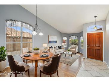Open-concept living room featuring hardwood floors, neutral paint, dining area and a welcoming front door at 10866 S Dreamy Dr, Goodyear, AZ 85338
