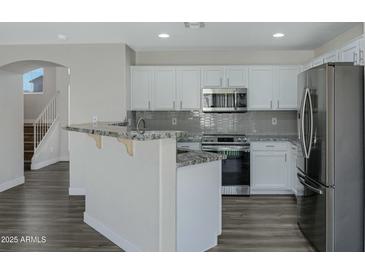 Modern kitchen featuring white cabinetry, stainless steel appliances, and a granite countertop breakfast bar at 15346 W Hearn Rd, Surprise, AZ 85379