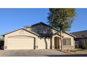 Traditional home exterior with three-car garage and desert landscaping under a clear blue sky at 2409 N 112Th Ln, Avondale, AZ 85392