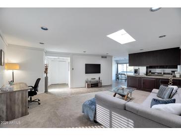Open living room features a skylight, carpet flooring, and access to a kitchen area at 6240 N 16Th St # 45, Phoenix, AZ 85016