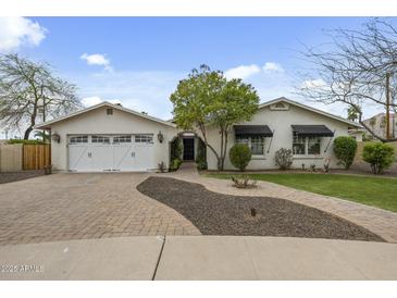 Charming single-story home with a white exterior, inviting landscaping, and a brick driveway at 6340 E Mitchell Dr, Scottsdale, AZ 85251