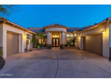 Stunning home with a circular driveway, meticulous landscaping, and a grand entrance, illuminated by soft lighting at 8427 E Preserve Way, Scottsdale, AZ 85266