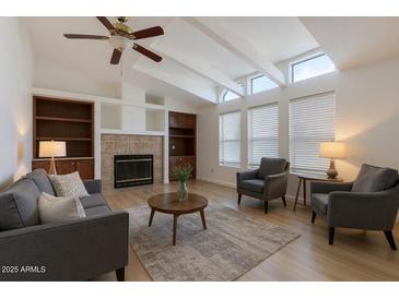Bright living room with vaulted ceilings, a cozy fireplace, and built in bookshelves at 2929 E Sequoia Dr, Phoenix, AZ 85050