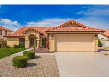 Charming front exterior features a well-manicured lawn, desert landscaping, and a tile roof at 7626 W Mcrae Way, Glendale, AZ 85308