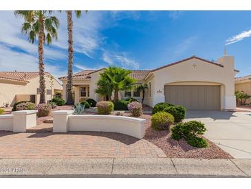 Charming single-story home featuring a landscaped front yard with palm trees and a two-car garage at 12835 W Chapala Ct, Sun City West, AZ 85375