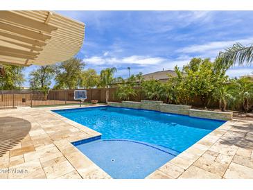 Inviting backyard pool with a waterfall feature, a basketball hoop, and a covered patio at 18543 E Purple Sage Dr, Queen Creek, AZ 85142
