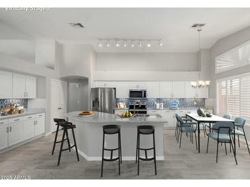 Staged kitchen with island, stainless steel appliances, tile backsplash, and dining area at 2698 E Carla Vista Dr, Gilbert, AZ 85295