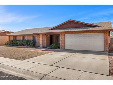 Charming brick home featuring a two-car garage, low maintenance yard, and inviting entryway at 5741 W Purdue Cir, Glendale, AZ 85302